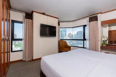 a hotel room with a bed and a flat screen tv at Grand Diamond Suites Hotel in Bangkok