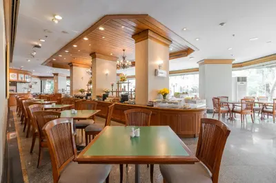 a restaurant with tables and chairs and a bar at Grand Diamond Suites Hotel in Bangkok