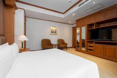 a hotel room with a bed and a flat screen tv at Grand Diamond Suites Hotel in Bangkok