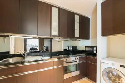 a kitchen with a sink and a washing machine at Emporium Suites by Chatrium in Bangkok