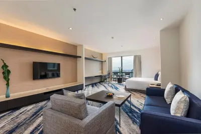 a hotel room with a bed and a couch and a tv at Emporium Suites by Chatrium in Bangkok