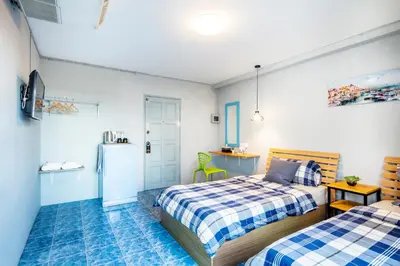 a bedroom with two beds and a refrigerator at Penyos Suite in Bangkok