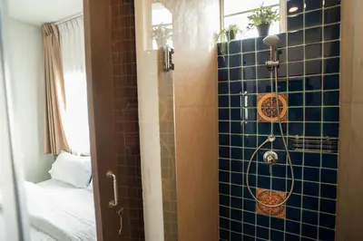 a bathroom with a shower with a blue tiled wall at Chetuphon Gate in Bangkok