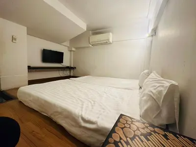 a bedroom with a white bed and a tv at Chetuphon Gate in Bangkok