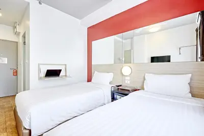 a hotel room with two beds and a mirror at Easy Planet Bangkok Asoke in Bangkok