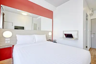 a bedroom with a large white bed and a mirror at Easy Planet Bangkok Asoke in Bangkok