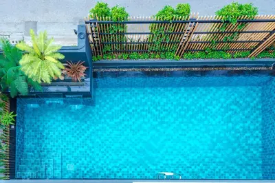 a blue swimming pool with a fence and plants at Penyos Mansion (Long Stay) in Bangkok
