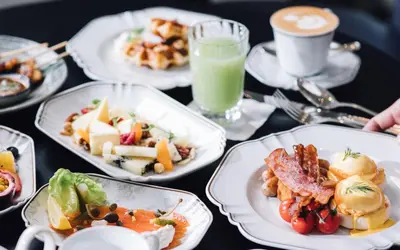 a table with plates of food and a cup of coffee at Rosewood Bangkok in Bangkok