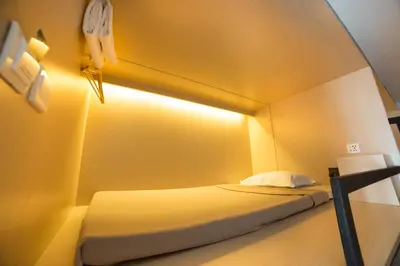 a bedroom with a bed with a light on the wall at Cubic Bed Pratunam in Bangkok