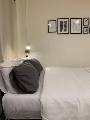 a bedroom with a bed with white sheets and pictures on the wall at House 116 in Bangkok