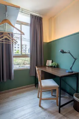 a desk with a lamp and a chair next to a window at Spacy BKK in Bangkok