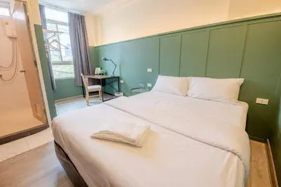a bedroom with a large white bed with a green wall at Spacy BKK in Bangkok