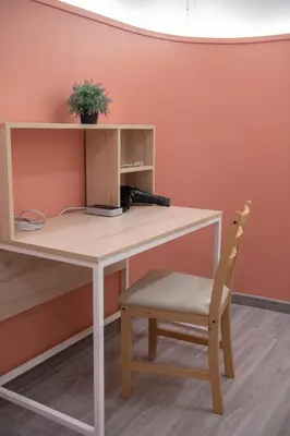 a wooden desk with a chair next to a wall at Spacy BKK in Bangkok