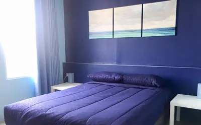 a bedroom with a purple bed with a blue wall at 43 Home in Bangkok Noi