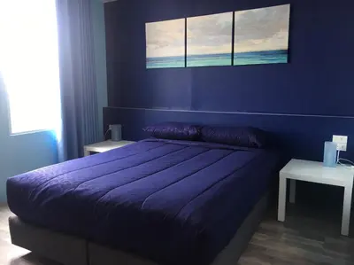 a blue bedroom with a bed with a purple comforter at 43 Home in Bangkok Noi