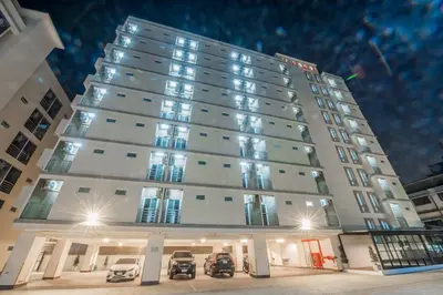 a tall white building with cars parked in front of it at U Sabai Hotel Bangkok in Bangkok