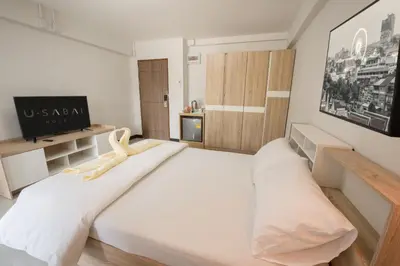 a bedroom with a large white bed and a television at U Sabai Hotel Bangkok in Bangkok