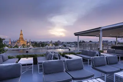 a rooftop patio with chairs and a view of a city at Sala Rattanakosin Bangkok in Bangkok
