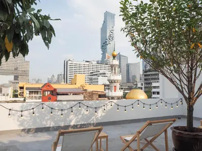 a balcony with two chairs and a tree with lights at Chocolate box mint in Bangkok