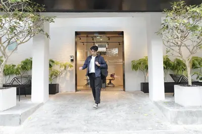 a man in a suit and tie walking into a building at Chocolate box mint in Bangkok