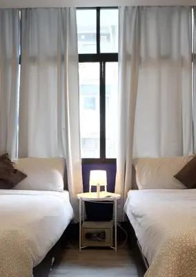 a room with two beds and a table with a lamp at Sleep with Me Bangkok - BTS Phra Khanong in Bangkok