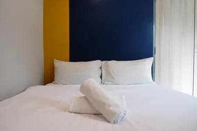 a white bed with white pillows and a blue wall at Sleep with Me Bangkok - BTS Phra Khanong in Bangkok