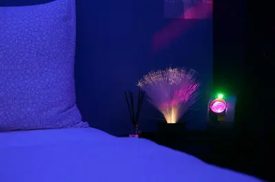 a dark room with a bed and a lighted alarm clock at Sleep with Me Bangkok - BTS Phra Khanong in Bangkok