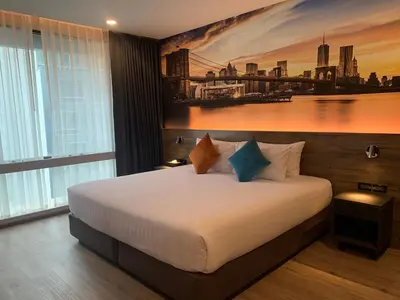a bedroom with a bed with a painting on the wall at Manhattan Hotel Bangkok in Bangkok
