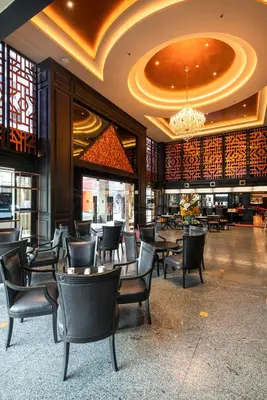 a restaurant with tables and chairs and a chandelier at Manhattan Hotel Bangkok in Bangkok