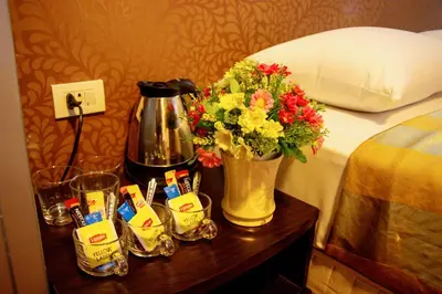 a table with a coffee maker and flowers on a bed at Visiting Card Hotel & Resort in Bangkok