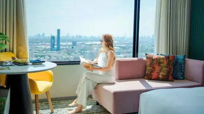 a woman sitting on a couch in a room with a window at Avani Sukhumvit Bangkok Hotel in Bangkok