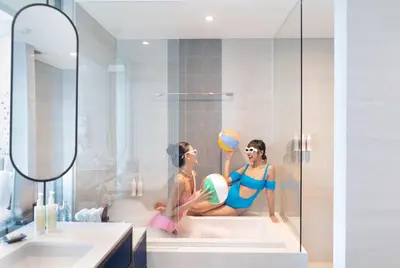 two women in a bathtub with a ball and a mirror at Avani Sukhumvit Bangkok Hotel in Bangkok