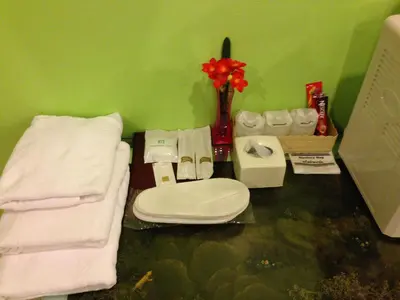 a bathroom with a toilet and a sink and towels at Penang Palace in Bangkok