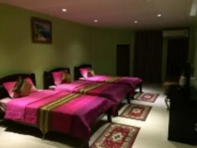 two beds in a green room with pink sheets at Penang Palace in Bangkok