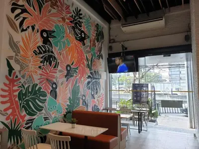 a restaurant with a colorful wall with tables and chairs at Aspira One Sutthisan in Bangkok