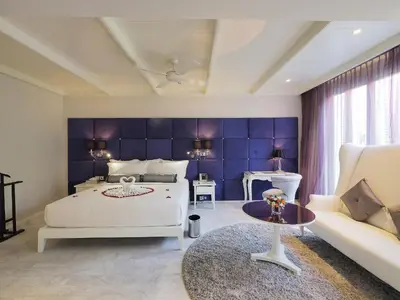a bedroom with a white bed and a blue wall at Hua Chang Heritage Hotel in Bangkok