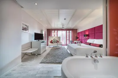 a hotel room with a tub and a bedroom at Hua Chang Heritage Hotel in Bangkok