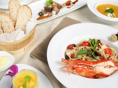 a table with a plate of food with shrimp and pasta at Hua Chang Heritage Hotel in Bangkok