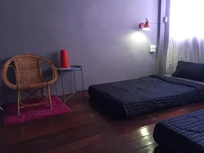 a room with two beds and a chair and a table at Hong hostel in Bangkok