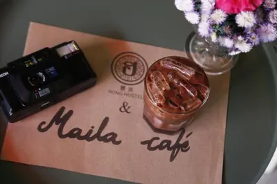a table with a camera and a drink on a napkin at Hong hostel in Bangkok