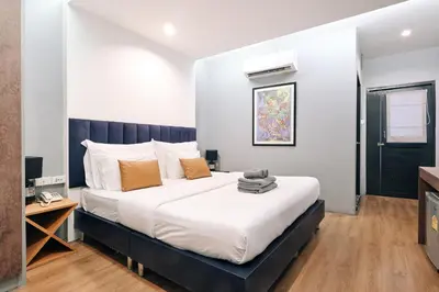 a bedroom with a large bed with white sheets and orange pillows at Castle Black Bangkok in Bangkok