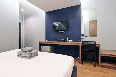a bedroom with a bed and a desk with a tv at Castle Black Bangkok in Bangkok