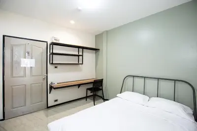 a bedroom with a bed and a desk and a door at Kaelyn Cozy Living in Bangkok