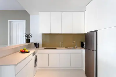 a kitchen with white cabinets and a black refrigerator at Dusit Suites Hotel Ratchadamri, Bangkok in Bangkok