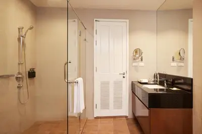 a bathroom with a shower and a sink and a glass door at Dusit Suites Hotel Ratchadamri, Bangkok in Bangkok