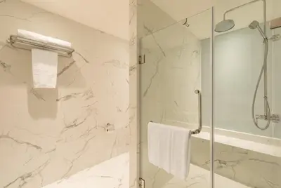 a white bathroom with a shower and a glass door at S Ram Leisure Hotel in Bangkok
