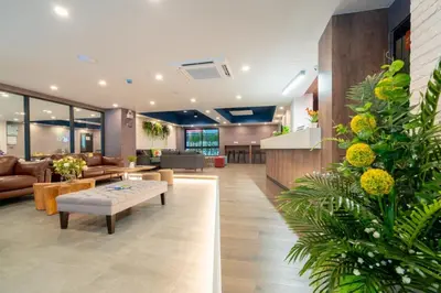 a lobby with a waiting area with a couch and tables at The Home Hotel SHA in Bangkok