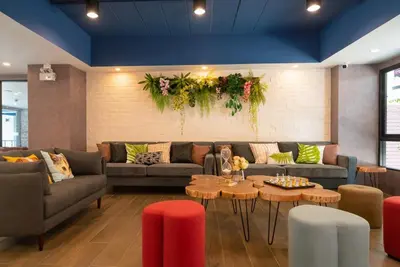 a living room with couches and tables and flowers at The Home Hotel SHA in Bangkok