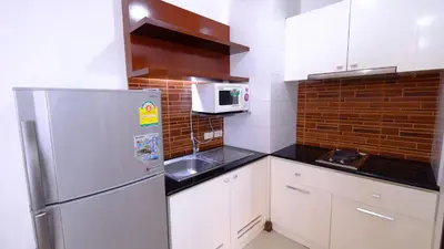 a small kitchen with a refrigerator and a microwave at Ploenchit Mansion in Bangkok