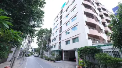 a tall white building on the side of a street at Ploenchit Mansion in Bangkok